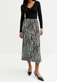 Černý žebrovaný dlouhý rukávový top spárovaný s midi sukní s černobílým vzorem zebřích pruhů. Černé lodičky se špičatým zakončením.
