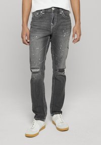 Grijze denim jeans met versleten plekken, verfspatten en contrasterende stiknaden. Gesneden in een rechte pijpvorm met voorzakken.