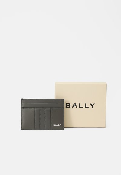 Cardholder gri din piele, cu multiple sloturi, marcă "BALLY", expus lângă o cutie bej cu text mare "BALLY".