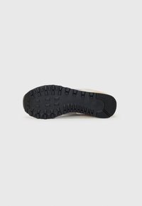 Black rubber shoe sole featuring a rugged tread pattern, with ridges and grooves for traction. Reinforced toe area and flat heel.