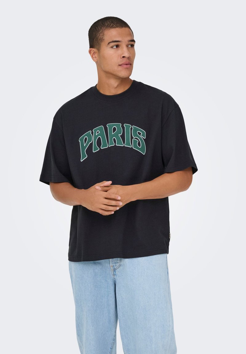 Zwart T-shirt met de tekst "PARIS" in groene letters op de voorkant. Heeft een comfortabele pasvorm en korte mouwen, gecombineerd met lichtblauwe spijkerbroek.