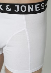 Weiße Baumwoll-Boxershorts mit einem schwarzen Bund, der den Markennamen "K & JONES" in Grau trägt, aus glattem Material und mit körpernahem Schnitt.
