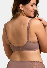 Soutien-gorge en tissu mauve doux avec bretelles réglables, design sans couture et fermeture à crochets. Accent en dentelle texturée sur les côtés.