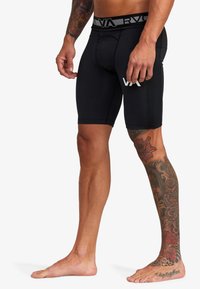 Schwarze Sportshorts mit einer taillierten Passform, elastischem Bund mit RVCA-Logo und Länge bis zur Mitte des Oberschenkels. Glatte Textur und keine Verzierungen.
