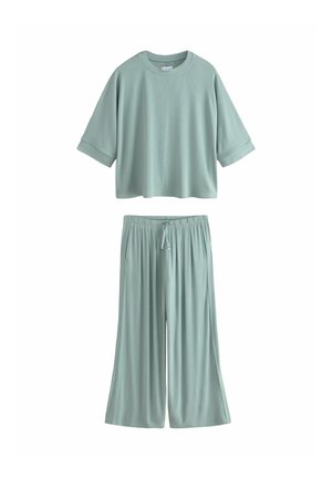 Világoszöld, laza szabású otthoni viselet szett, rövid ujjú, kerek nyakú felsővel és széles szárú, zsinóros nadrággal.