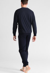 Conjunto de ropa de estar en casa de color azul marino que incluye una camiseta de manga larga con estampado y pantalones a juego con puños elásticos y un ajuste relajado.