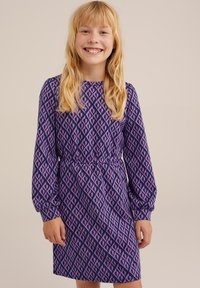 Lila klänning med långa ärmar, med ett geometriskt mönster i rosa och en midjesöm. Tyget verkar slätt med en lätt struktur.