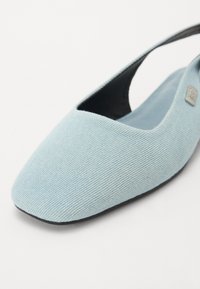 Svetlo modre platnene ravne čevlje s koničastim nosom in slingback dizajnom. Teksturirana tkanina s gladko notranjostjo in diskretno kovinsko podrobnostjo logotipa.