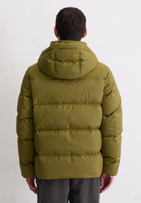 Oliwkowo-zielona pikowana kurtka z kapturem, z pikowanym przeszyciem zapewniającym izolację. Gładka, teksturowana tkanina. Widok od tyłu.