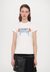 Balta īsām piedurknēm T-krekls ar grafisku zīmējumu ziliem un melniem toņos, ar ziedu akcentiem un tekstu "VERSACE JEANS COUTURE ROCK."
