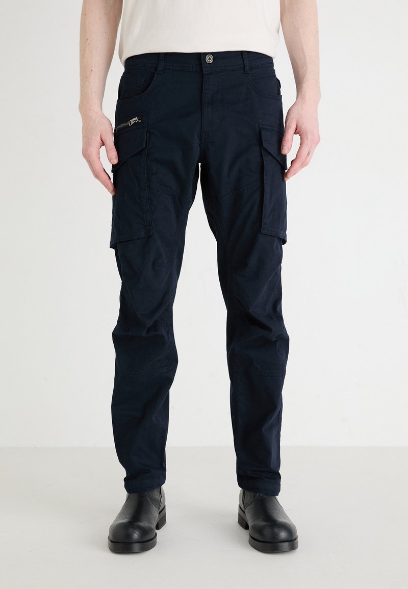 Navy Cargo-Hosen mit mehreren Taschen, Reißverschlussdetails und einem lockeren Schnitt. Hergestellt aus strapazierfähigem Stoff mit glatter Textur.