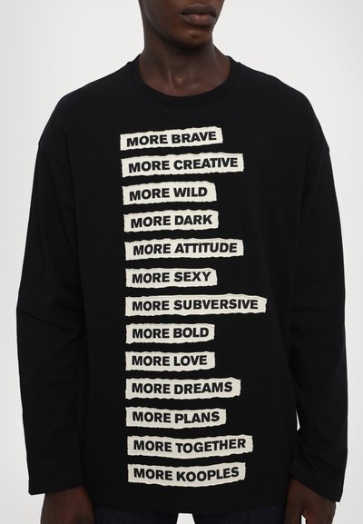 Black long-sleeve t-shirt with a crew neck featuring white, torn-paper style text slogans vertically aligned in the center.