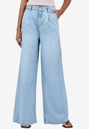 Jean large bleu clair en denim, avec taille haute, devant plissé et poches. Le tissu a une finition douce et texturée.