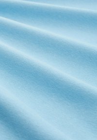 Hellblaue Baumwollstoffe mit einer glatten Textur, die sanfte Falten und eine einheitliche Farbe zeigen.