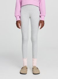 Leggings grigie in tessuto elasticizzato. Abbinate a calzini rosa chiaro a costine con bordi arricciati e scarpe beige slip-on.