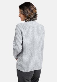 Grauer gerippter Strickpullover mit hohem Kragen, gesenkten Schultern und lässiger Passform. Weicher Stoff und subtile Details entlang der Nähte.