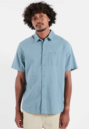 Chemise à manches courtes avec boutons, en tissu bleu clair présentant un motif texturé subtil et une poche poitrine à rayures verticales.
