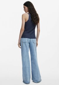 Tielko s námorníckym vzorom a priliehavým strihom, skombinované s svetlomodrými širokými nohavicami. Hladká textura, ležérny štýl a žiadne viditeľné kovania.