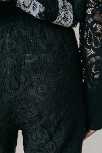 Fekete csipkebársony nadrág bonyolult virágmintákkal és változatos textúrákkal rendelkezik, testhezálló fazonban, finom hátsó zseb részlettel.