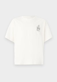 T-shirt de algodón blanco con un corte holgado, mangas cortas y un pequeño gráfico floral negro en el lado izquierdo del pecho. Textura suave.