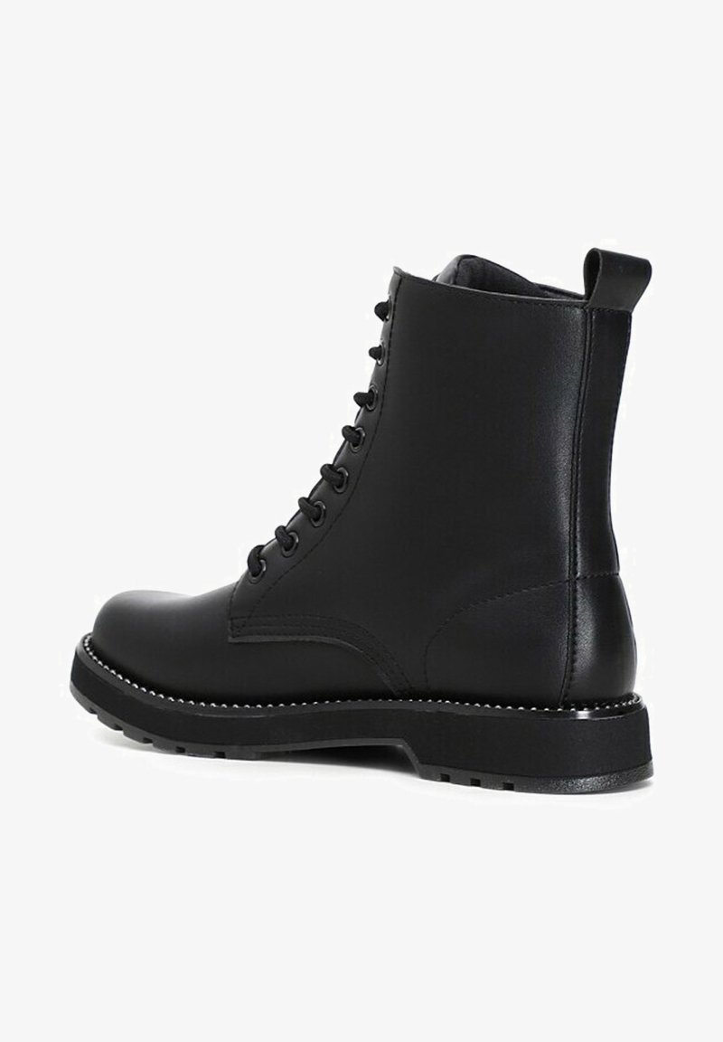 Bottine en cuir noir avec lacets sur le devant, languette à l’arrière, semelle épaisse à crampons et coutures décoratives sur le bord.