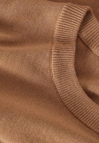 Tissu de pull tricoté marron doux avec un gros plan sur le détail du col roulé côtelé et plié.