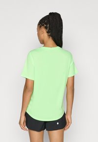 Ανοιχτό πράσινο κοντομάνικο μπλουζάκι με στρογγυλή λαιμόκοψη, φτιαγμένο από λείο ύφασμα· συνδυασμένο με μαύρο σορτς, χωρίς ορατά σχέδια ή μεταλλικά στοιχεία.