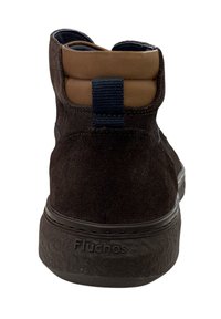 Bottine en daim marron avec une semelle texturée, présentant un col rembourré beige, des accents navy et un logo "Fluchos" embossé au niveau du talon.