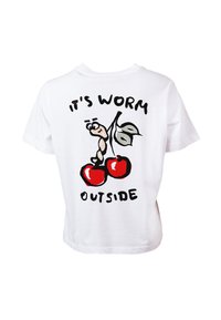 T-shirt blanc avec un ver de dessin animé suspendu à une tige de cerise entre deux cerises et le texte "IL FAIT VERMOUILLE DEHORS."
