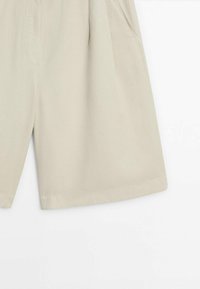 Vaaleanbeiget shortsit, joissa on väljä istuvuus, valmistettu pehmeästä kankaasta. Ominaisuuksiin kuuluvat sivutaskut ja hienovarainen rakenne, jossa on siistit, suorat helmat.