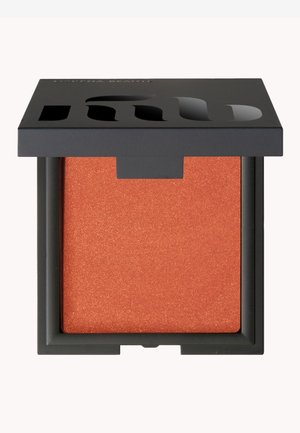 Orange shimmer-blush i en fyrkantig dosa med ett matt svart lock. Dosen har en utskärning för att visa produkten.