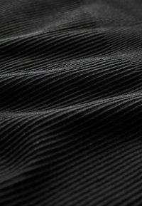 Tessuto nero a righe orizzontali pronunciate e morbido al tatto, che mostra una leggera lucentezza alla luce naturale.