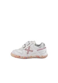 Zapatilla blanca con dos cintas de velcro, acentos plateados y una suela texturizada con motas coloridas. En el lateral tiene un detalle bordado en rosa.