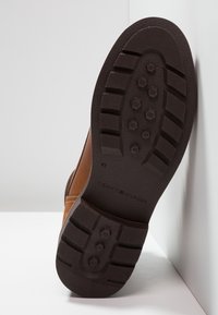 Hnědá kožená podrážka boty s texturovanou gumovou podrážkou s hexagonálním vzorem a značkou "TOMMY HILFIGER", velikost 41.