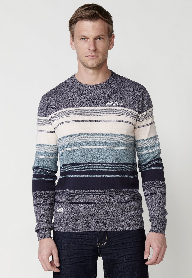 Gebreide trui in marineblauw, blauw en crème strepen. Heeft een ronde hals en een textuurafwerking met een klein logo op de borst.