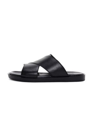 Męskie czarne skórzane klapki na płaskiej podeszwie z krzyżującymi się paskami na białym tle.