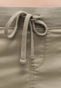 Μπεζ υφασμάτινο παντελόνι με ριμπ ύφανση στη μέση και δέσιμο με κορδόνι στο κέντρο μπροστά.