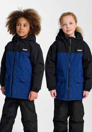 Twee kinderen dragen capuchonjacks met een blauwe romp en zwarte mouwen, gemaakt van gladde stof. De jacks hebben voorzakken en elastische manchetten.
