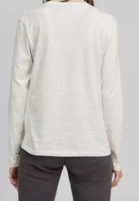 Lys grå langærmet t-shirt med rund halsudskæring, blød tekstur og en afslappet pasform, præsenterer et enkelt og ensartet stofmønster.