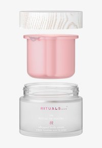 Klar glassbehållare med rosa innerlock och texturerat vitt ytterlock. Etiketten visar varumärke och produktnamn i rosa och vitt.