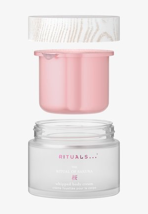 Przezroczyste szklane naczynie z różową wewnętrzną pokrywką i teksturowaną białą zewnętrzną pokrywką. Etykieta zawiera logo i nazwę produktu w kolorach różowym i białym.