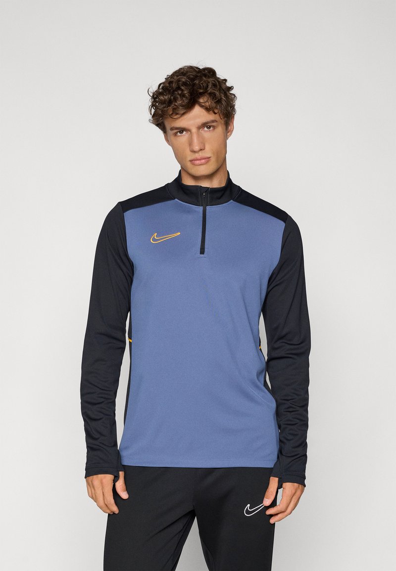 Nike zip-up langærmet top med blå front, sorte ærmer og gule detaljer. Lavet af letvægtsstof med en glat tekstur.