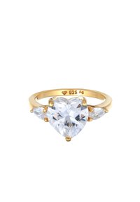 Guldbelagt ring med en hjerteformet klar ædelsten i midten, flankeret af to pærformede detaljer. Metallet er mærket "925 Ag."