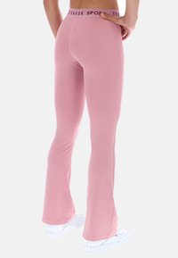 Różowe legginsy w kształcie dzwonów wykonane z elastycznego materiału z markowym paskiem w talii. Gładka faktura, dopasowany krój i wydłużona długość do kostek.