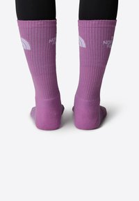 Calcetines morados hasta la rodilla con una textura acanalada y talón reforzado. Presenta detalles del logotipo en blanco en el lado exterior.