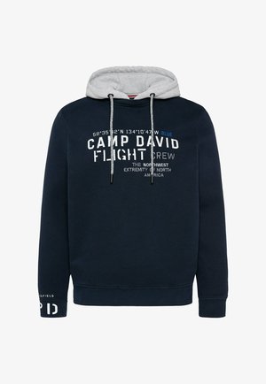 Sudadera marina con forro gris, presentada con texto blanco y azul, cordones ajustables y puños acanalados. Muestra logotipos y coordenadas geográficas.