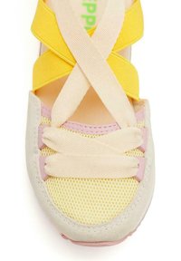 Zapatilla colorida con tiras cruzadas amarillas y rosas, parte superior de malla transpirable y una suave punta gris con acentos en tonos pastel.