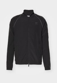 Black zip-up jacket with high collar, made of lightweight fabric. Features white accents, side pockets, and a logo on the left chest.