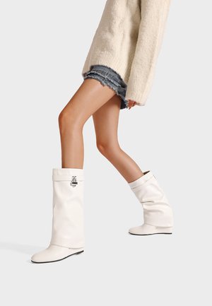 Stivali bianchi al ginocchio in materiale lucido, con bordino pieghevole, accento in metallo laterale e suola piatta.