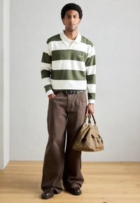 Roheline-valgete triipudega pika varrukaga polo, koos lahtiste pruunide pükstega. Riietuse lõpetavad pruunid kingad ja beež kott, millel on aksendid.